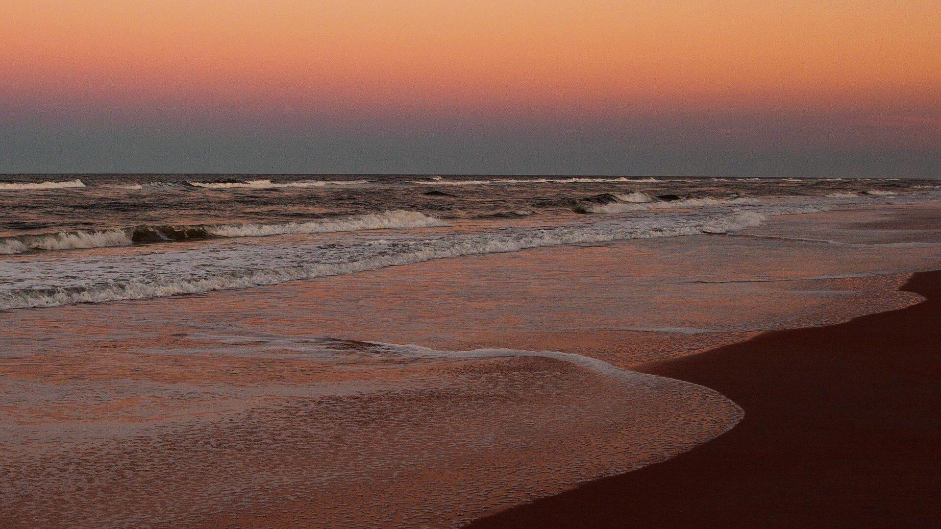 The Atlantic shoreline at dusk, low light across wet sand