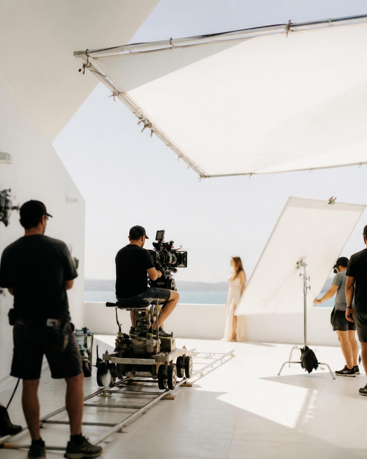 A bright daylight film set with diffusion frames and a cinema camera on a dolly